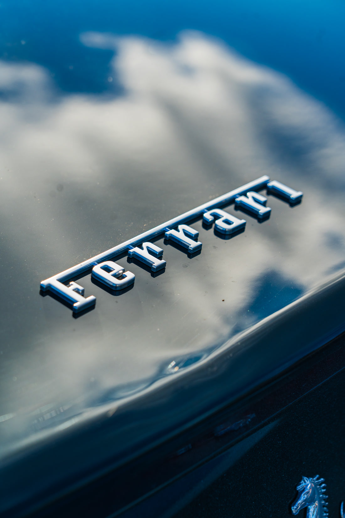 Emblema de Ferrari sobre la carrocería, con el cielo reflejado